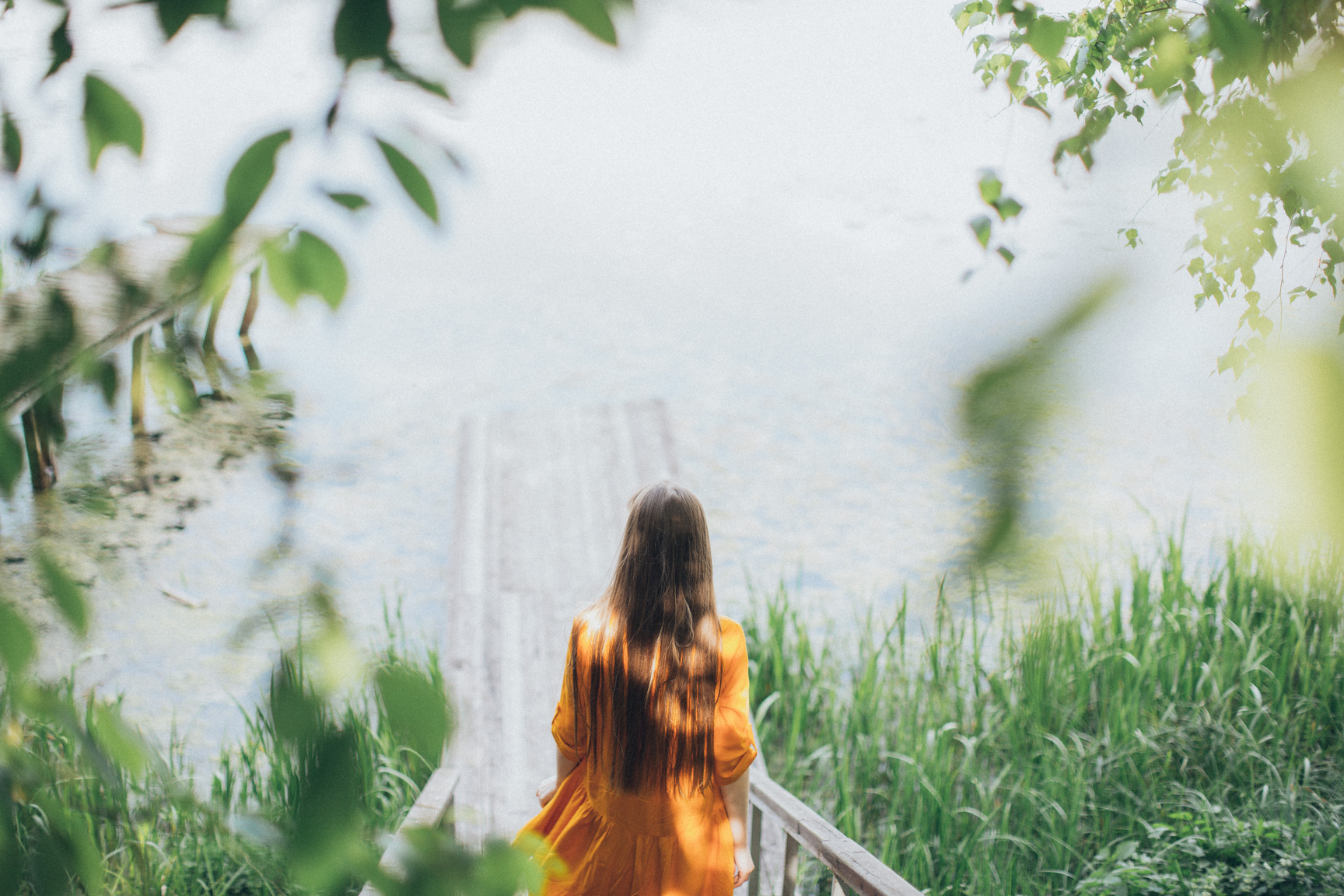 Young woman walking down on wooden path towards lake